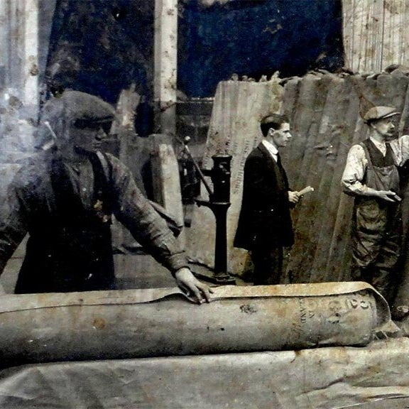 Archive photograph of workers rolling bolts of waxed cotton at the British Millerain mill.